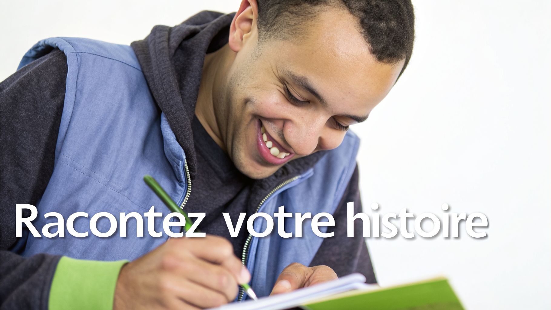 Jeune homme souriant écrivant dans un cahier vert avec un stylo, encourageant à raconter son histoire.